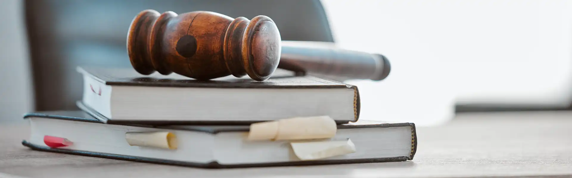 Ein Holzhammer liegt auf mehreren gestapelten Bücher mit Lesezeichen